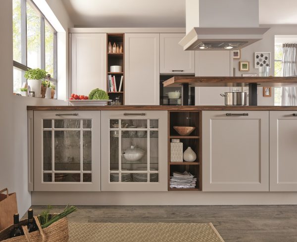 Landhaus Kücheninsel mit Unterbauschränken und verkleideter Abzugshaube - zwei Türen verglast, zwei mit klassisch matt-weißer Front in Kassettenoptik.