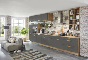 Lange Küchenzeile mit schwarzen Fronten, hellem Sockel und heller Holzarbeitsplatte.
