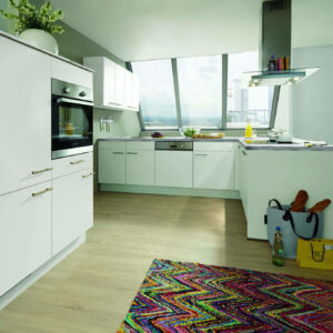 Winkelküche (weiß) mit heller, grauer Arbeitsplatte und freihängendem Dunstabzug. Im Vordergrund zwei hohe Küchenschränke mit Backofen, im Hintergrund weiße Hängeschränke.