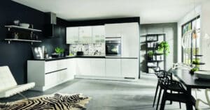 Grifflose weiße Hochglanz-Lack Küche in L-Form mit schwarzer Arbeitsplatte.